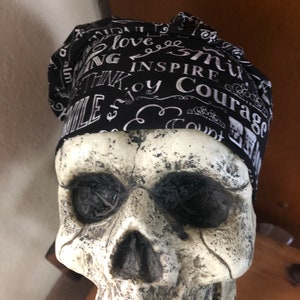 May include: Black and white fabric skull cap with the words "Smile", "Love", "Think", "Inspire", "Enjoy", "Courage", and "Count" printed on it.