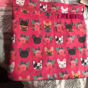 May include: Pink fabric tote bag with a repeating pattern of French Bulldogs and floral bouquets. The bag has a pink ribbon with a sparkly bow.
