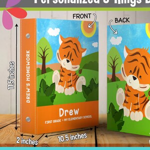 May include: Personalized 3-ring binder with a tiger illustration. The front cover features the name "Drew" and the text "First Grade - My Elementary School". The back cover has a similar tiger illustration. The spine is orange and says "Drew's Homework".