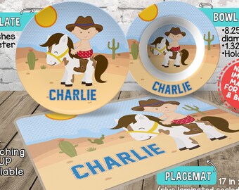 May include: Personalized children's dinnerware set with a cowboy riding a horse theme. The set includes a 10-inch plate, a bowl that holds 12 ounces, and a 17 x 11 inch placemat. The placemat has a laminated sealed edge and a free activity printed on the back. All items feature the name "Charlie" and a cowboy riding a horse illustration.