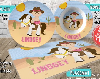 May include: Personalized children's placemat, plate, and bowl set with a cowgirl riding a horse design. The placemat is blue with a brown border and features a pink name "LINDSEY". The plate and bowl are white with a brown border and feature the same design. The bowl is 8.25 inches in diameter and 1.32 inches deep. The placemat is 17 inches by 11 inches. The set is made of high-performance polymer, free of formaldehyde, BPAs, and DEHPs. It is FDA and NSF approved for food contact and is microwave, oven, and dishwasher safe.