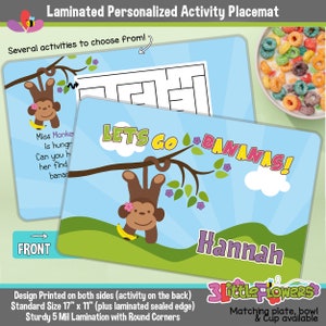 May include: A blue and green laminated placemat with a monkey hanging from a tree branch. The placemat has the text "Let's Go Bananas!" and the name "Hannah". The back of the placemat has a maze activity. The placemat is 17 inches by 11 inches.