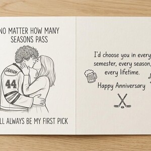 May include: A white greeting card with black line art. The left side shows a couple kissing, with the person on the left wearing a hockey jersey labeled Graham 44. Text reads: NO MATTER HOW MANY SEASONS PASS YOU'LL ALWAYS BE MY FIRST PICK. Happy Anniversary.