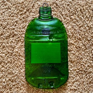 May include: A green glass bottle shaped cutting board with the text "Charles Tanqueray & Co." embossed on the front.