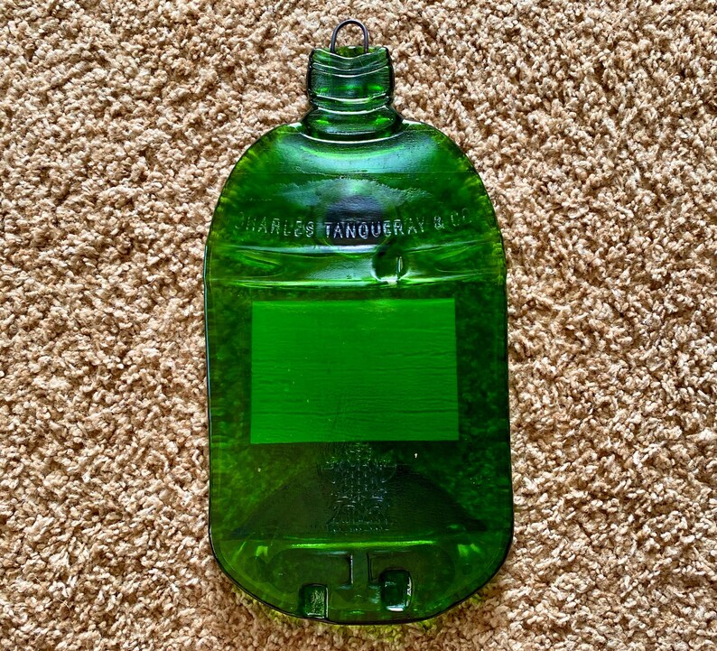 May include: A green glass bottle shaped cutting board with the text "Charles Tanqueray & Co." embossed on the front.