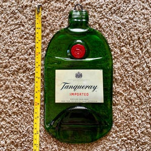May include: A green glass bottle shaped like a gin bottle with a red wax seal. The bottle has a label that reads "Tanqueray Imported, Distilled Four Times, Made from the World's Finest Botanicals."