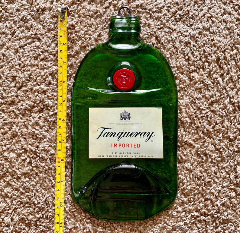 May include: A green glass bottle shaped like a gin bottle with a red wax seal. The bottle has a label that reads "Tanqueray Imported, Distilled Four Times, Made from the World's Finest Botanicals."