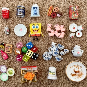 May include: A collection of miniature toys and figurines, including a red soda cup, a can of peanuts, a bag of ice, a box of cereal, and a SpongeBob SquarePants figure. Also includes dice, plates, and a thimble.