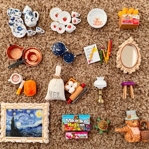 Puede incluir: Una colección de accesorios en miniatura para casa de muñecas, que incluye una pintura enmarcada de "La noche estrellada" de Van Gogh, un juego de té, utensilios de cocina, un espejo y un oso de peluche con una cesta. Otros artículos incluyen una lámpara, caramelos y una bolsa.