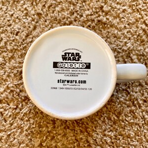 May include: A white ceramic mug with a handle, featuring the Star Wars logo and the Galerie brand. The bottom of the mug displays text including "Dishwasher & Microwave Safe" and "Made in China."