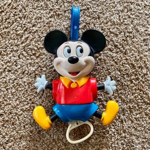 Może przedstawiać: Biały ceramiczny kubek z czarnym uchwytem i napisem "But First, Coffee" pogrubioną, czarną czcionką. Kubek jest ustawiony na rozmytym tle, sugerującym przytulne otoczenie.