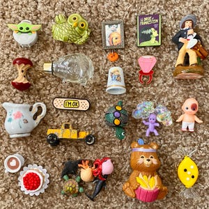 以下が含まれることがあります： ヨーダのフィギュア、緑色のフクロウ、ミニチュアの額縁、フランケンシュタインの花嫁の本、男性のフィギュアなど、小さな装飾品のコレクション。 その他のアイテムには、指ぬき、指輪、小さな黄色の車が含まれます。