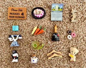 May include: A collection of miniature decorative items, including a laptop, a bell with ABC letters, a lock, a telephone, a bunny, a seahorse, carrots, donuts, a snail, a teacup with a dog, a sign that says "Please Hide Packages From Husband", and two wooden hangers.