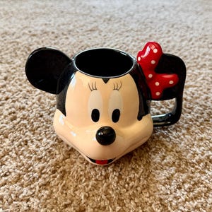 May include: A set of three ceramic mugs with a speckled, matte finish. The mugs are in shades of cream, light gray, and dark gray. Each mug has a simple, minimalist design, perfect for coffee or tea.