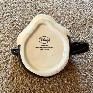 May include: A set of three ceramic mugs with a speckled, matte finish. The mugs are in shades of cream, light gray, and dark gray. Each mug has a simple, minimalist design and a rounded handle.