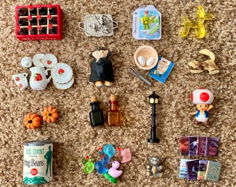 May include: A collection of miniature toys and accessories, including a red Coca-Cola crate, a silver tray, a Peter Pan toy, a yellow balloon dog, a miniature doll, and a can of Big Giant String Beans.