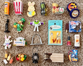 May include: A collection of miniature toys and accessories, including a Pringles can, popcorn box, bunny, Buzz Lightyear figure, and doll accessories. Other items include a teddy bear, a leprechaun, and a miniature lantern.