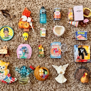 以下が含まれることがあります： 野球カード、Poweradeのボトル、Planters Cheez Ballsの缶、Heart Bonesというタイトルの本、Venomのフィギュアなど、ミニチュアのフィギュアや食品のコレクション。