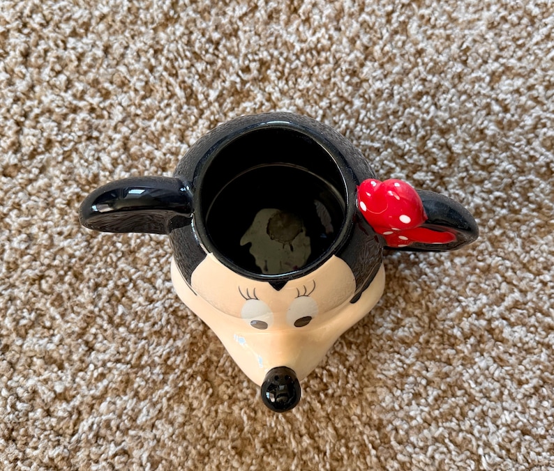 May include: A white ceramic mug with a black handle and the text "But First, Coffee" in a bold, black font. The mug is on a white surface.