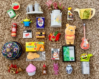May include: A collection of miniature toys and collectibles, including a Winnie the Pooh figure, a guitar, a can of potato chips, a blue and white decorative jar, and a green alien toy.