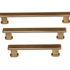May include: Three gold-toned cabinet pulls with a rectangular shape and a brushed finish.