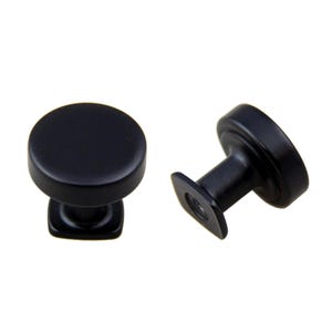 May include: Two black cabinet knobs with a round top and a square base. The knobs are made of metal and have a matte finish.