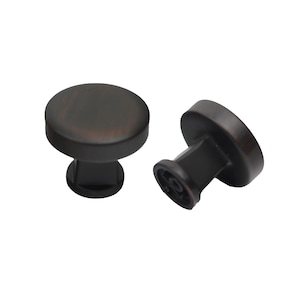 May include: Two black cabinet knobs with a round top and a square base. The knobs have a brushed finish.