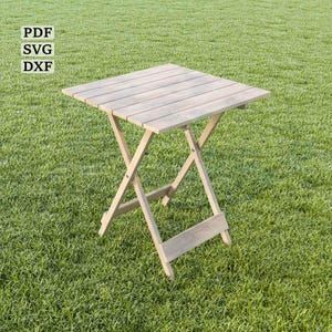 May include: A wooden folding table with a natural wood finish. The table is set up on a green grassy lawn.