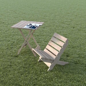 May include: A wooden folding chair and table set on a green grassy lawn. The table has a magazine on top.