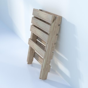 May include: A wooden folding chair with a natural finish. The chair is made of slats of wood and is folded up against a white wall.