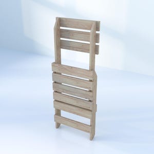 May include: A wooden folding chair with a light brown finish. The chair is folded and standing upright.