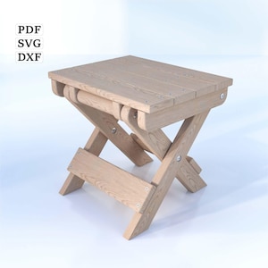 Puede incluir: Un taburete plegable de madera clara con un diseño sencillo. El taburete está hecho de tablones de madera y tiene una base en forma de cruz.