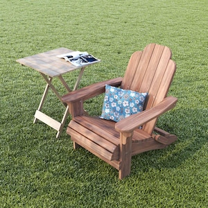 May include: A wooden adirondack chair with a blue and white floral pillow on a green grassy lawn. A small wooden folding table with a magazine on top is next to the chair.