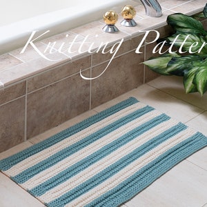 May include: A knitted bathroom rug with blue and white stripes. The rug is lying on a tiled floor in a bathroom. The text "Knitting Pattern" is written in white on a brown tile.