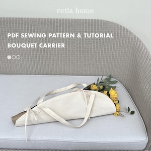 May include: A cream fabric bouquet carrier with long handles, containing yellow sunflowers and green foliage. The carrier has a brown paper base. Text on the image reads "PDF Sewing Pattern & Tutorial Bouquet Carrier."