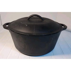 May include: A black cast iron Dutch oven with a lid and two side handles. The lid has a single handle on top. The pot is round and has a slightly tapered shape. This cookware is ideal for slow cooking and baking.