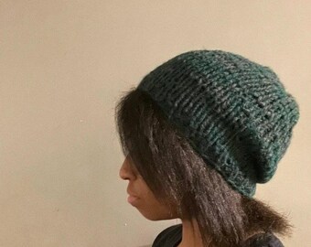 May include: A person wearing a dark green knitted beanie hat.