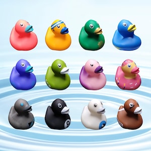May include: A collection of 12 colorful rubber duck toys. The ducks are in various colors, including pink, yellow, green, blue, purple, and brown. Some of the ducks have designs on them, such as a football, a donut, and a shamrock.