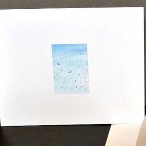 May include: A white card with a blue watercolor painting of a sky with clouds. The painting is framed with a white border.