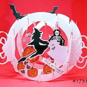 May include: A white and orange Halloween-themed paper decoration. The design features a witch on a broom, pumpkins, a skeleton, and a ghost. The text "Trick or Treat!" is also included.
