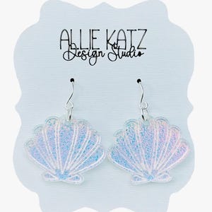 May include: A pair of iridescent seashell earrings with silver hooks. The earrings are displayed on a light blue card with the text "ALLIE KATZ Design Studio" in black script.