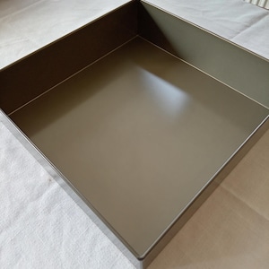 May include: A white ceramic mug with a black handle and the text "But First, Coffee" in a black, bold font. The mug is on a white surface.