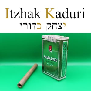 Puede incluir: Un paquete de cigarrillos Noblesse Virginia Filter con un dise&ntilde;o verde y blanco, junto a un cigarrillo marr&oacute;n. El texto "Itzhak Kaduri" se muestra encima del paquete en ingl&eacute;s y hebreo.