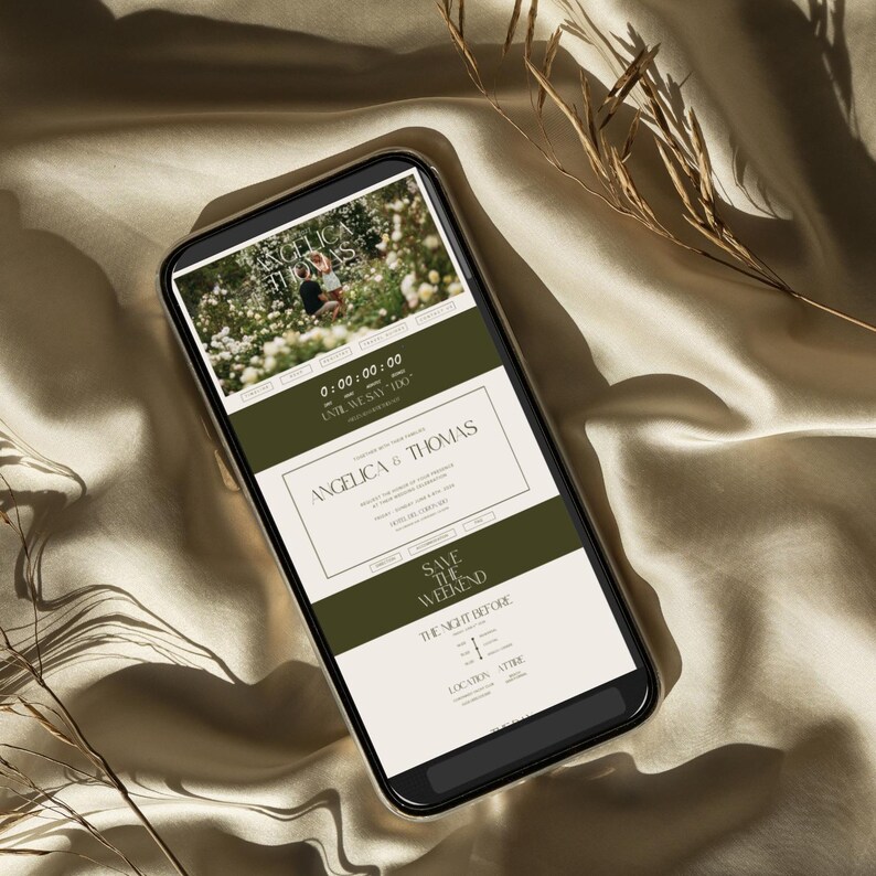 May include: A smartphone displays a wedding invitation design. The invitation features the names "ANGELICA & THOMAS" in a serif font, with the text "SAVE THE WEEKEND" below. The design includes a photo and a timer that reads "0:00:00:00". The phone rests on a satin surface.