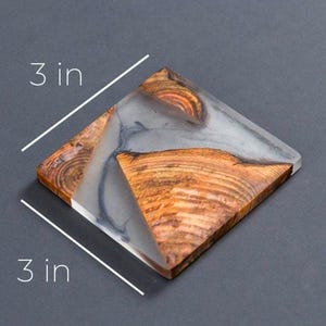 Op de afbeelding: Een vierkante onderzetter gemaakt van hout en helder hars met een grijs en bruin marmerpatroon. De onderzetter is 7,6 cm bij 7,6 cm.