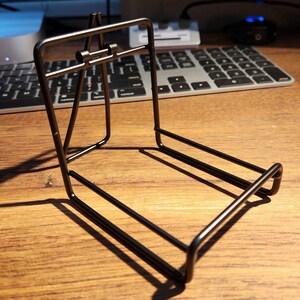 Op de afbeelding: Een zwarte metalen standaard voor het tentoonstellen van items zoals boeken, foto's of kleine sculpturen.