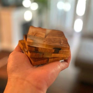 Op de afbeelding: Set van vier houten onderzetters met transparante harsaccenten. De onderzetters zijn op elkaar gestapeld en hebben een natuurlijke houtnerf.