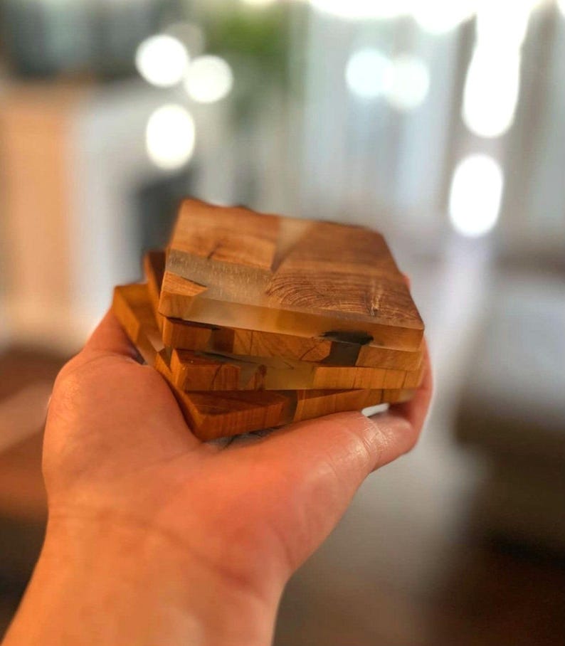 Op de afbeelding: Set van vier houten onderzetters met transparante harsaccenten. De onderzetters zijn op elkaar gestapeld en hebben een natuurlijke houtnerf.