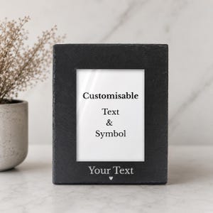May include: A black slate picture frame with a white interior. The frame has the words "Customisable Text & Symbol" and "Your Text" printed on it. A small heart symbol is below the words "Your Text".