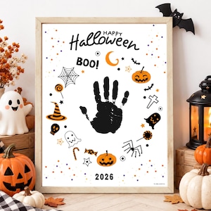 Op de afbeelding: Een ingelijste witte poster met een zwarte handafdruk in het midden, omringd door oranje en zwarte Halloween-iconen zoals pompoenen, spoken, een spinnenweb, een heksenhoed en snoepjes. De tekst luidt Happy Halloween, BOO! en 2026.